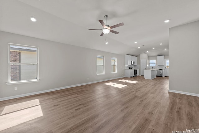 unfurnished living room featuring light hardwood / wood-style flooring, vaulted ceiling, and ceiling fan