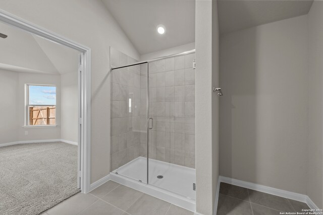 bathroom with tile patterned floors, a shower with shower door, and vaulted ceiling