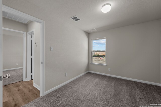 carpeted spare room with a textured ceiling