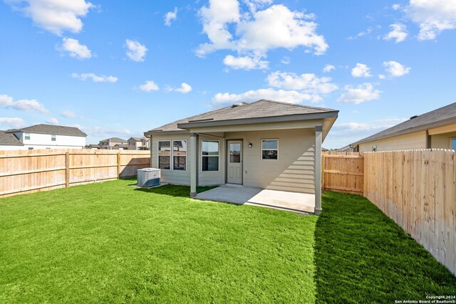 rear view of house featuring a lawn, a patio, and central AC