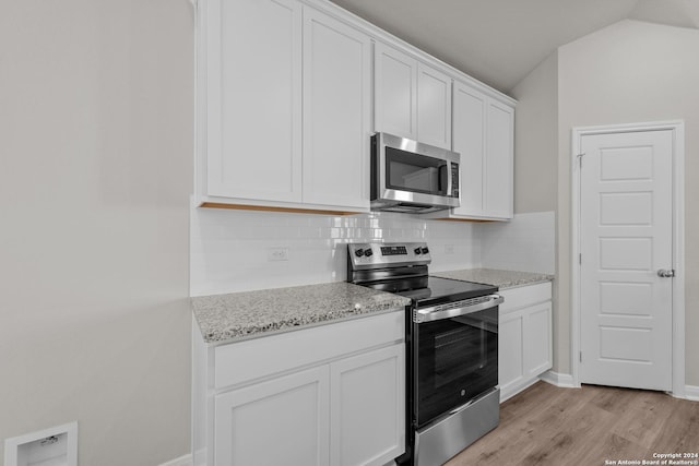 kitchen with white cabinets, appliances with stainless steel finishes, tasteful backsplash, and light stone countertops