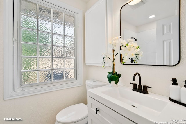 bathroom featuring a wealth of natural light, toilet, and large vanity