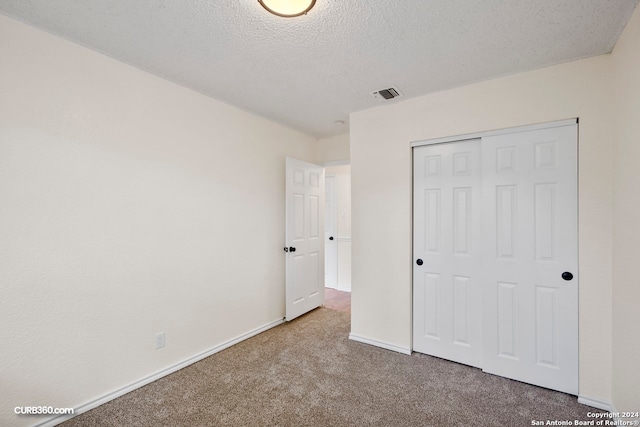 unfurnished bedroom featuring a closet, a textured ceiling, and carpet flooring