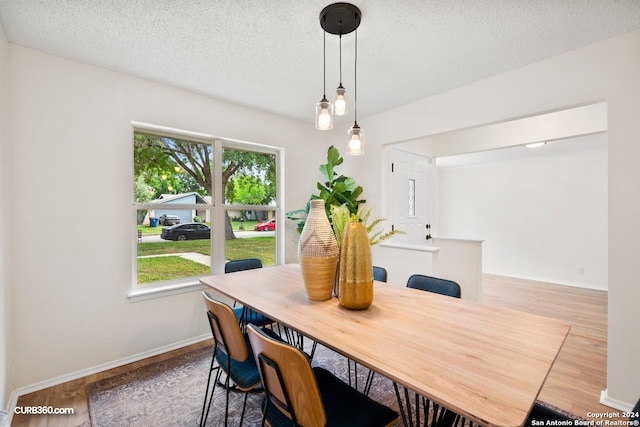 dining space with hardwood / wood-style flooring and a textured ceiling