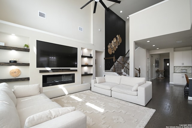 living room featuring wood-type flooring, built in shelves, ceiling fan, and a high ceiling