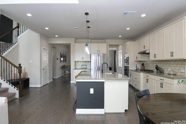 kitchen with a center island with sink, white cabinets, hanging light fixtures, and dark wood-type flooring