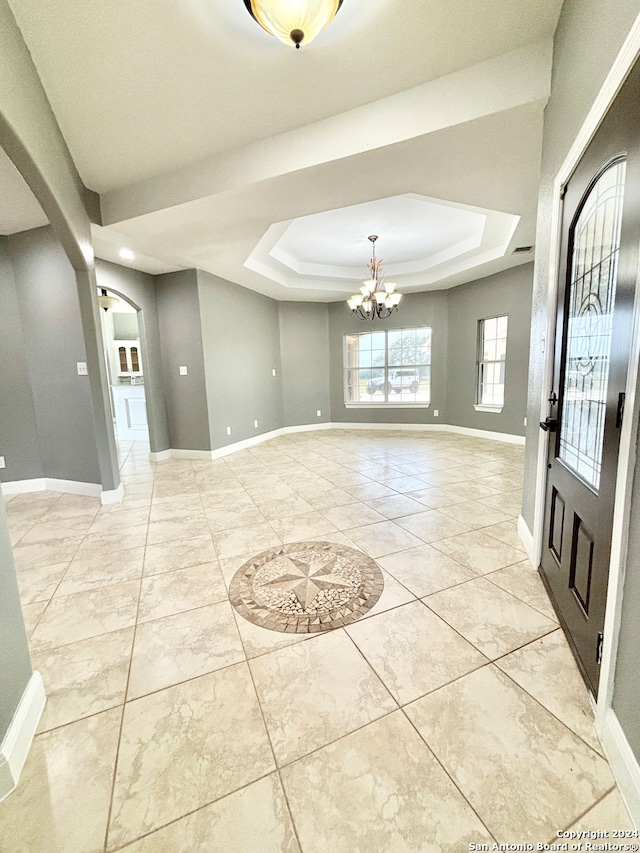 tiled foyer with a chandelier and a tray ceiling