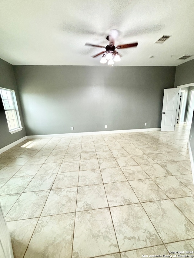 unfurnished room featuring a textured ceiling, light tile patterned floors, and ceiling fan