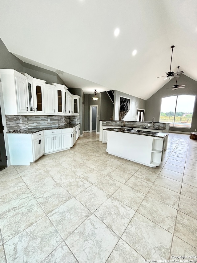 kitchen featuring ceiling fan, light tile patterned flooring, vaulted ceiling, and white cabinetry