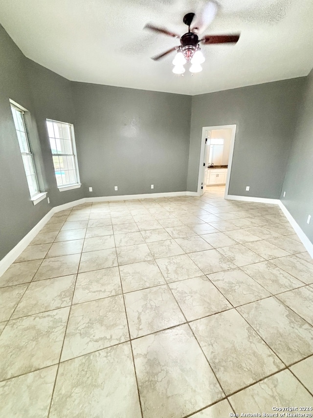 tiled spare room with a textured ceiling and ceiling fan