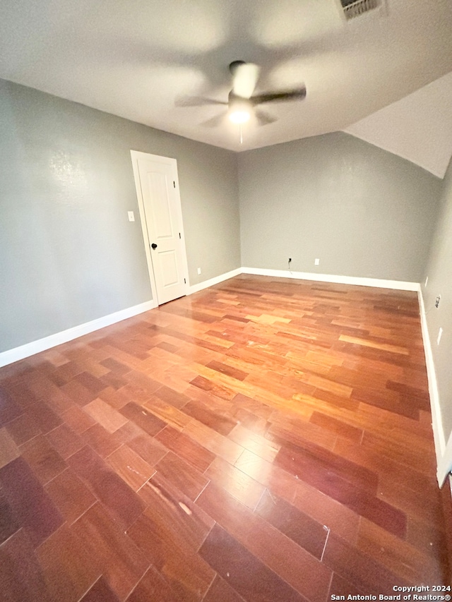 empty room with ceiling fan, hardwood / wood-style flooring, and vaulted ceiling