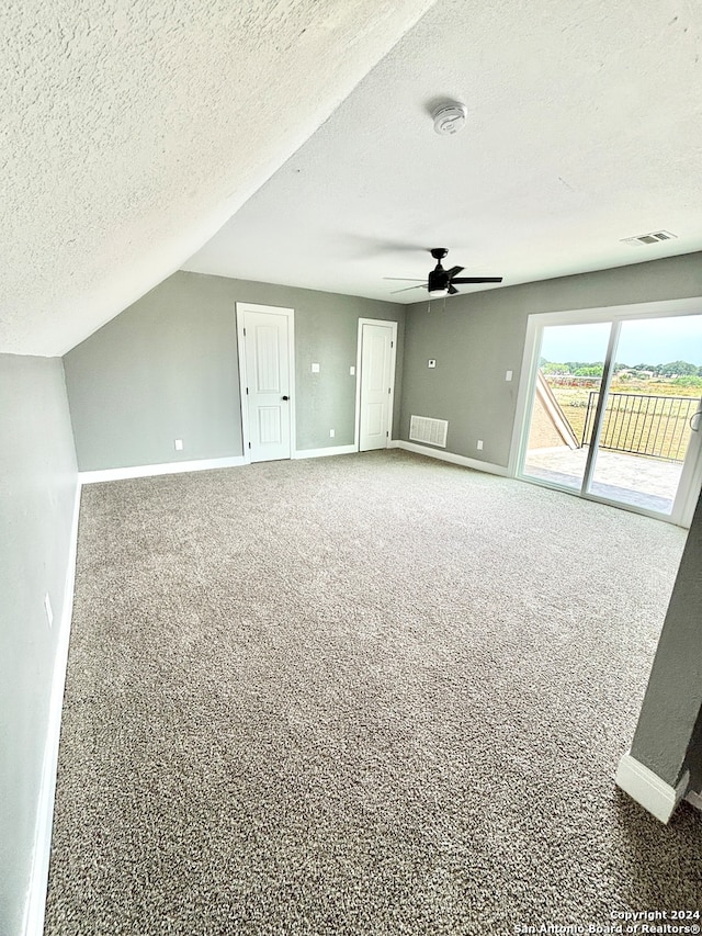 additional living space featuring ceiling fan, vaulted ceiling, a textured ceiling, and carpet floors