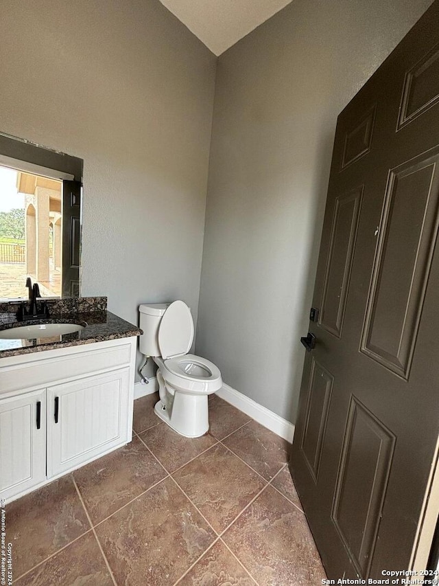 bathroom with toilet, vanity, and tile patterned flooring