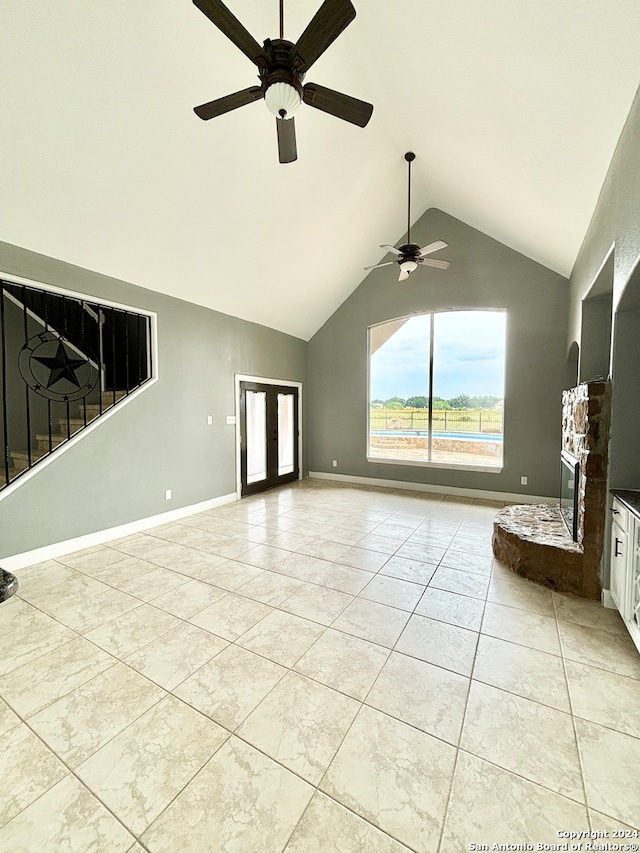 unfurnished living room with ceiling fan, a fireplace, french doors, and light tile patterned floors