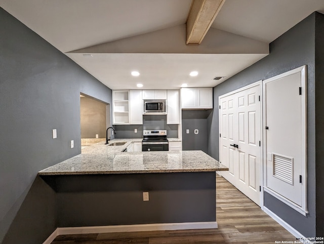 kitchen with kitchen peninsula, vaulted ceiling with beams, wood-type flooring, sink, and appliances with stainless steel finishes