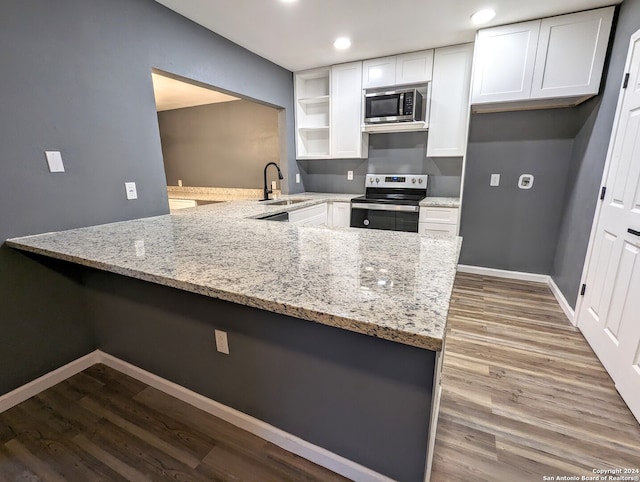 kitchen featuring stainless steel appliances, sink, hardwood / wood-style flooring, and kitchen peninsula