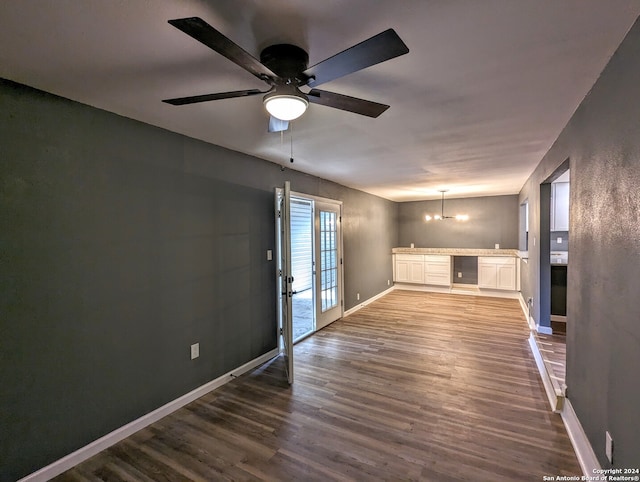 unfurnished living room with ceiling fan with notable chandelier and dark hardwood / wood-style flooring