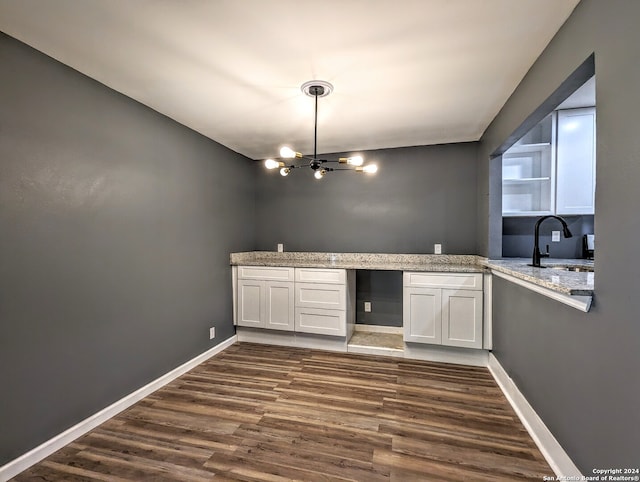 kitchen featuring light stone countertops, an inviting chandelier, white cabinets, dark hardwood / wood-style floors, and sink