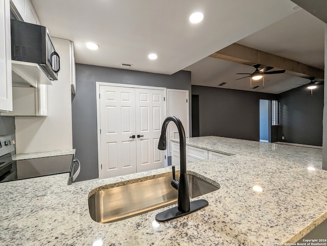 kitchen with light stone counters, ceiling fan, range, white cabinets, and sink