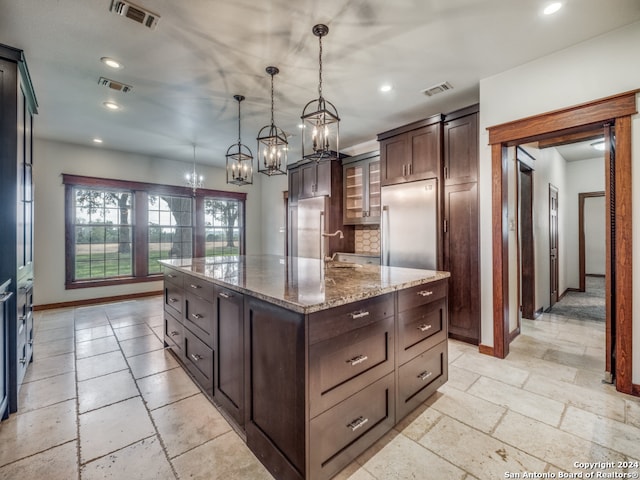 kitchen with a center island, built in refrigerator, pendant lighting, tasteful backsplash, and light tile flooring