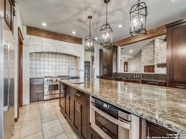 kitchen with stainless steel appliances, dark brown cabinets, light stone counters, decorative light fixtures, and sink