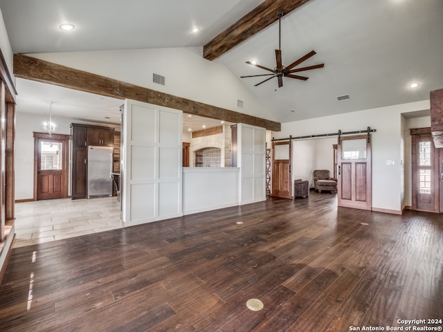 unfurnished living room featuring wood-type flooring, a barn door, ceiling fan, and beam ceiling