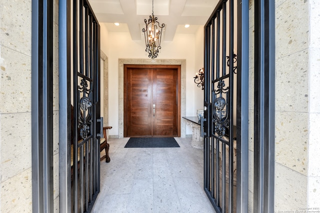 foyer featuring an inviting chandelier and coffered ceiling