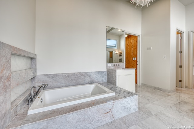 bathroom featuring a high ceiling, tile flooring, tiled bath, and vanity