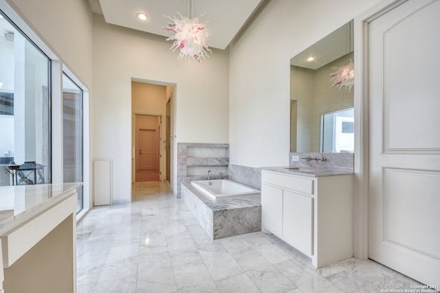 bathroom featuring tile flooring, tiled tub, and vanity