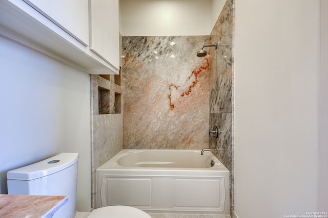 bathroom featuring tiled shower / bath and toilet