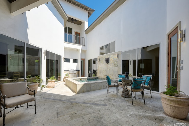 view of patio featuring an in ground hot tub and a balcony