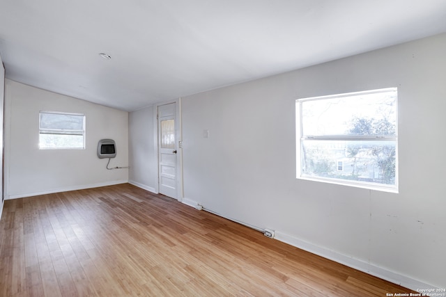 empty room with a healthy amount of sunlight, vaulted ceiling, and light wood-type flooring