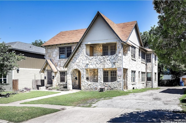 tudor-style house featuring a front lawn