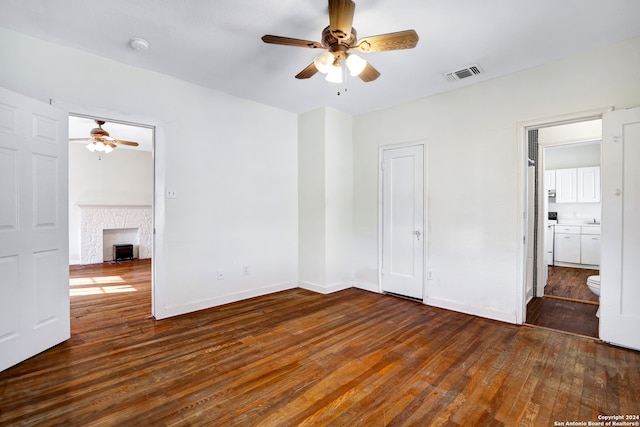 unfurnished bedroom with ceiling fan, ensuite bathroom, and dark wood-type flooring