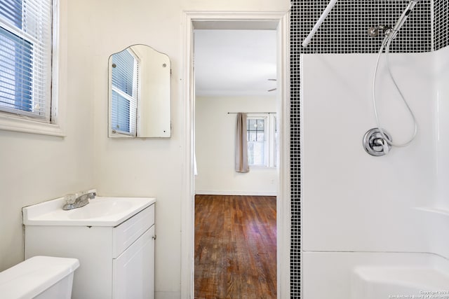 full bathroom featuring vanity with extensive cabinet space, hardwood / wood-style floors, toilet, and tiled shower / bath combo