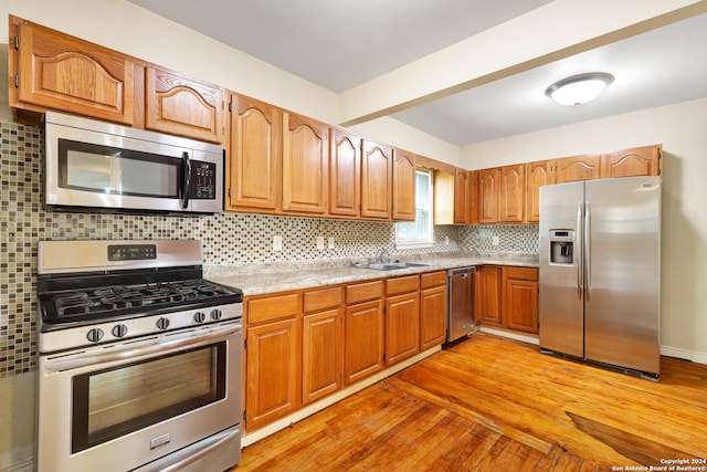 kitchen featuring sink, backsplash, light wood-type flooring, and stainless steel appliances