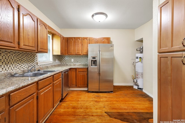 kitchen featuring stainless steel appliances, light hardwood / wood-style floors, gas water heater, and sink