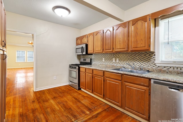 kitchen with appliances with stainless steel finishes, plenty of natural light, sink, and wood-type flooring