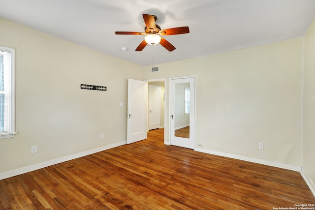 empty room with a wealth of natural light, ceiling fan, and dark hardwood / wood-style floors