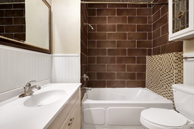 full bathroom with tiled shower / bath, vanity with extensive cabinet space, and toilet