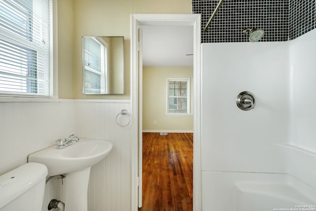 bathroom featuring tiled shower, hardwood / wood-style flooring, and toilet