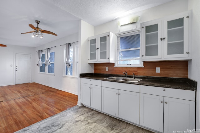 kitchen featuring light hardwood / wood-style flooring, backsplash, ceiling fan, white cabinetry, and sink