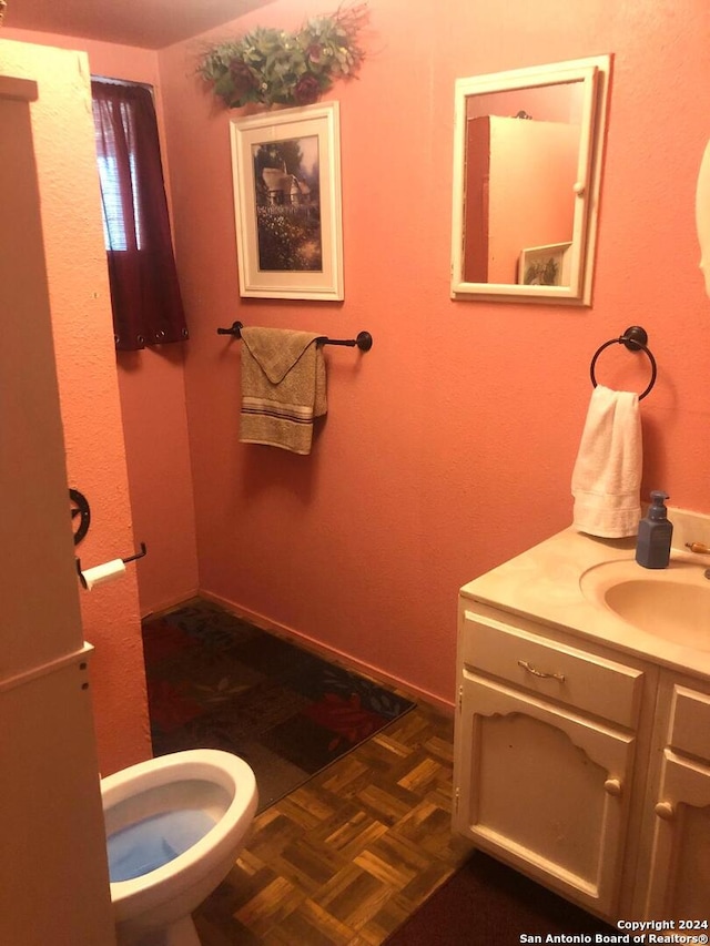 bathroom featuring toilet, vanity, and parquet flooring