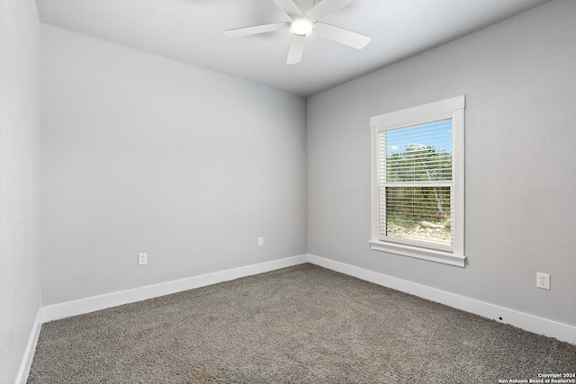 empty room featuring ceiling fan and dark carpet