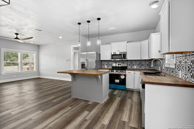 kitchen featuring a center island, stainless steel appliances, dark hardwood / wood-style flooring, and wood counters