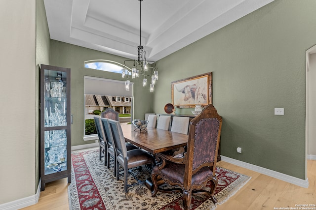 dining room with an inviting chandelier, hardwood / wood-style floors, and a raised ceiling