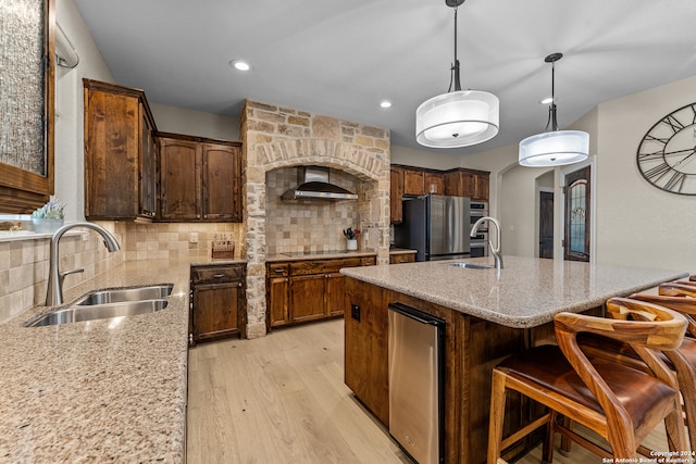 kitchen featuring stainless steel fridge, tasteful backsplash, light wood-type flooring, pendant lighting, and sink