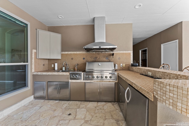 kitchen featuring light tile flooring, tasteful backsplash, refrigerator, white cabinetry, and wall chimney exhaust hood