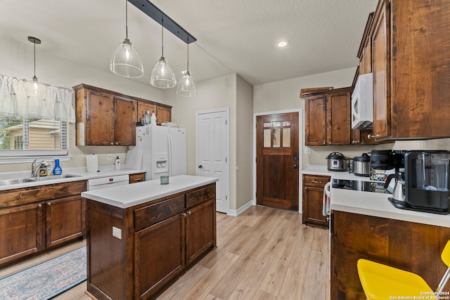 kitchen featuring a center island, light hardwood / wood-style floors, white appliances, decorative light fixtures, and sink