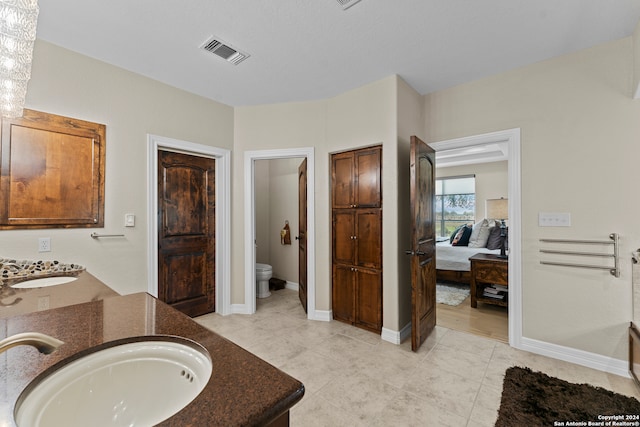 bathroom with double sink vanity, wood-type flooring, and toilet